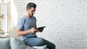 Photo d'un homme utilisant une tablette sur un canapé